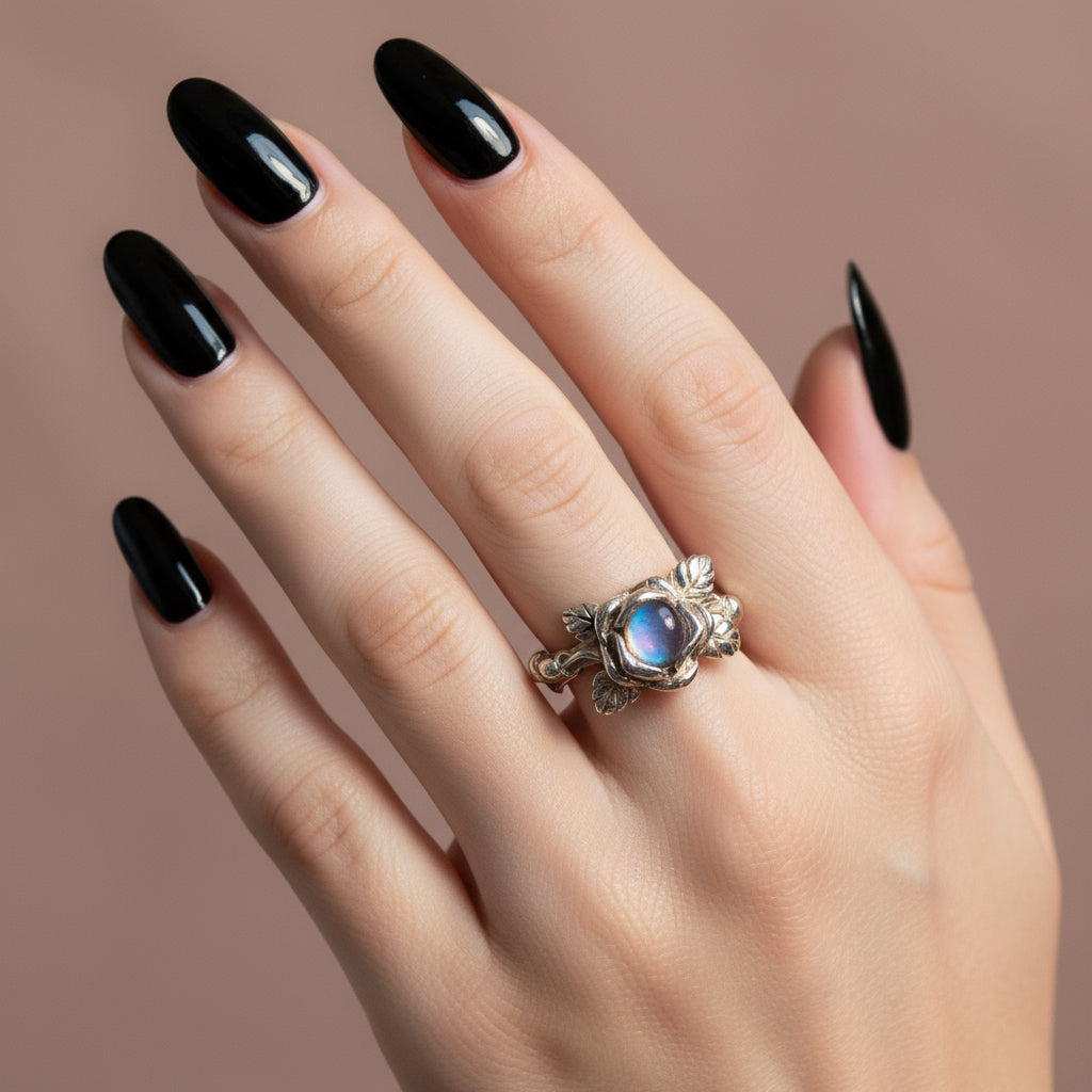 Silver ring with a blue gemstone on a finger against an orange and brown striped background